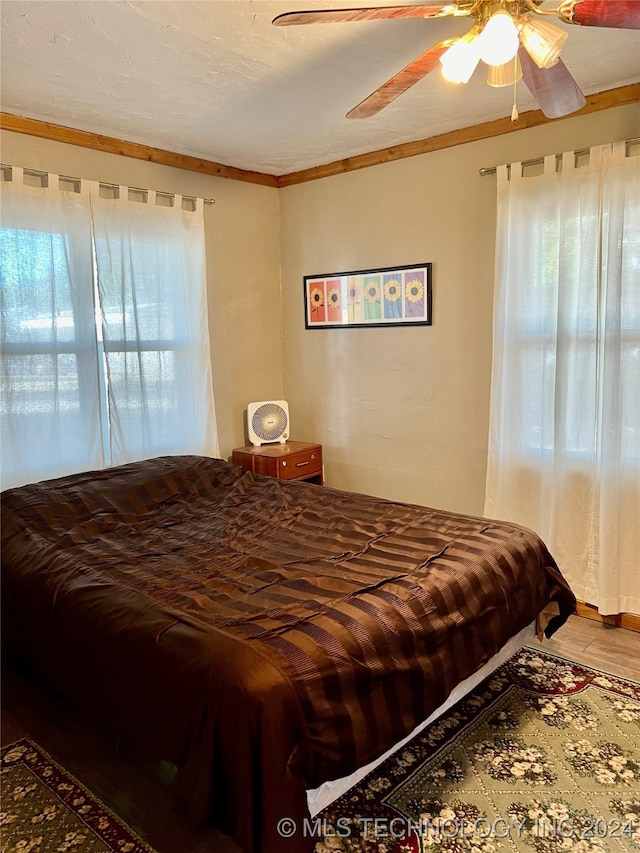 bedroom with crown molding, wood-type flooring, and ceiling fan