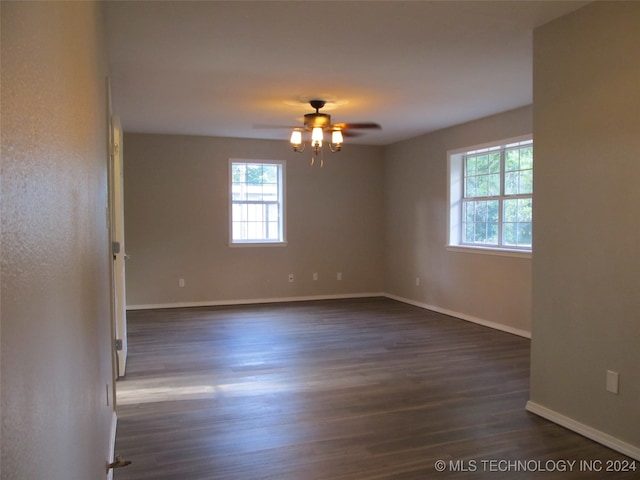 empty room with ceiling fan, plenty of natural light, and dark hardwood / wood-style flooring