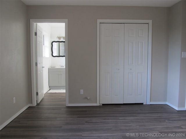 unfurnished bedroom with ensuite bath, a closet, and dark hardwood / wood-style flooring