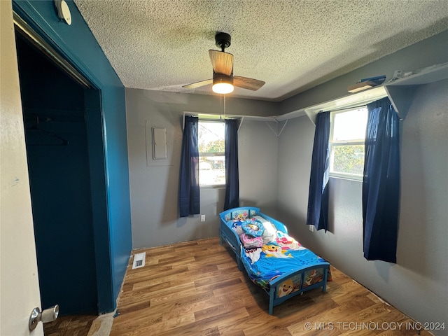 bedroom with multiple windows, ceiling fan, and hardwood / wood-style flooring