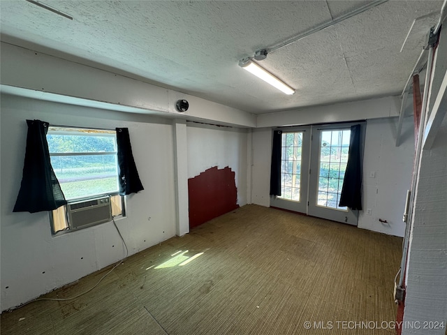 unfurnished room featuring cooling unit, a textured ceiling, and plenty of natural light