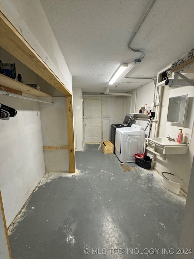 basement featuring a textured ceiling, sink, and washing machine and dryer