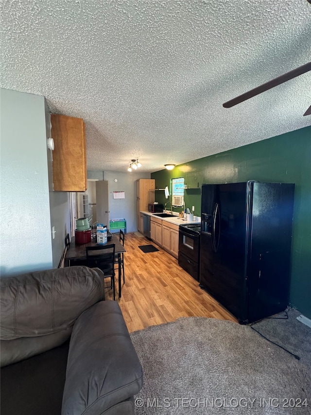 living room with a textured ceiling, sink, and light hardwood / wood-style floors