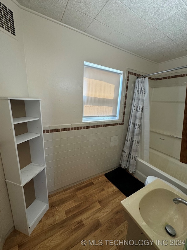 full bathroom with tile walls, vanity, shower / bath combination with curtain, hardwood / wood-style flooring, and toilet