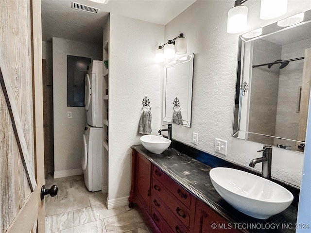 bathroom with vanity, tiled shower, tile patterned floors, and stacked washing maching and dryer