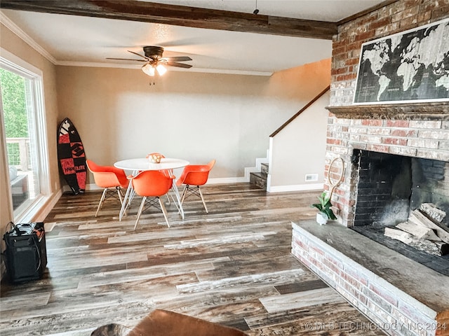 dining room with brick wall, beamed ceiling, a fireplace, hardwood / wood-style floors, and ceiling fan