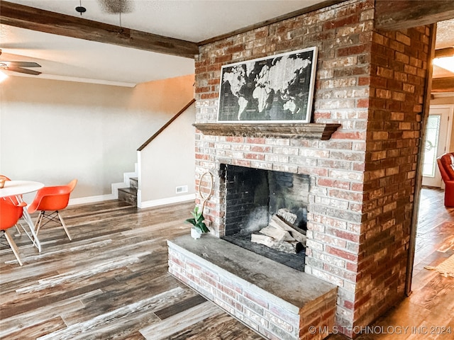 living room with a brick fireplace, wood-type flooring, ceiling fan, and beam ceiling