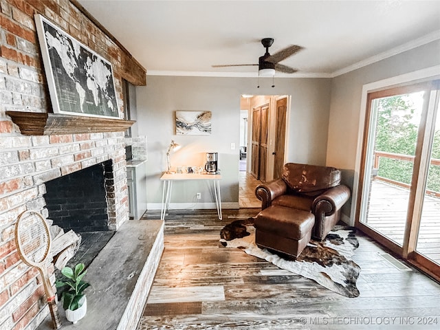 living room with brick wall, ceiling fan, hardwood / wood-style floors, and a brick fireplace