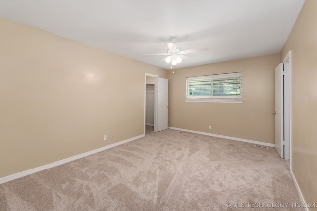 unfurnished bedroom featuring ceiling fan, a closet, and light colored carpet