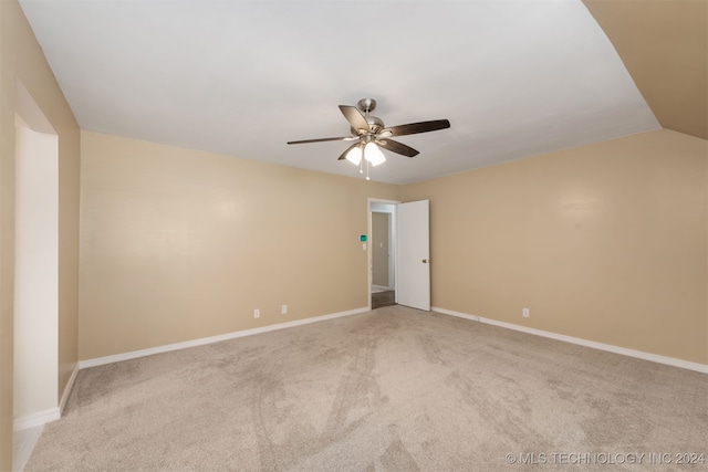 spare room with ceiling fan, light colored carpet, and vaulted ceiling