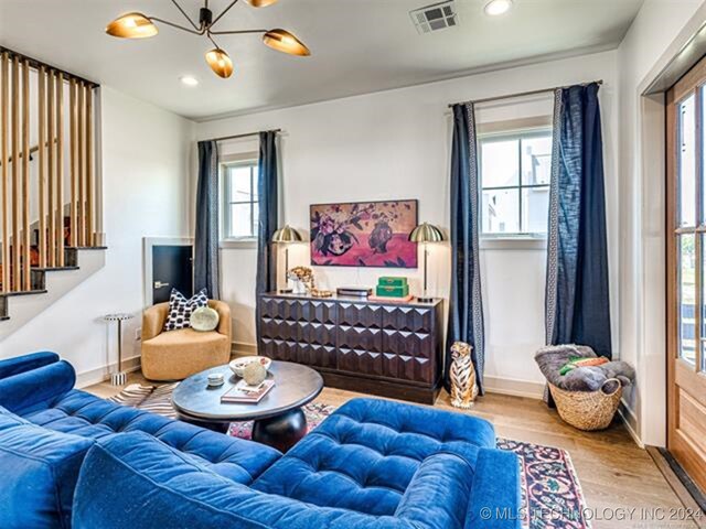 living area with visible vents, stairway, wood finished floors, an inviting chandelier, and recessed lighting