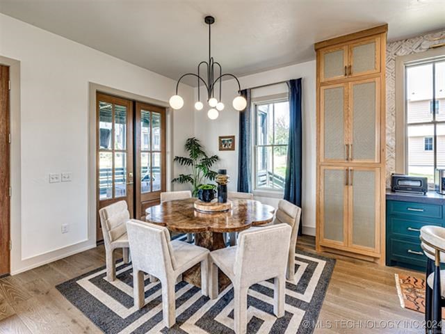 dining room featuring light wood-style floors, french doors, baseboards, and an inviting chandelier