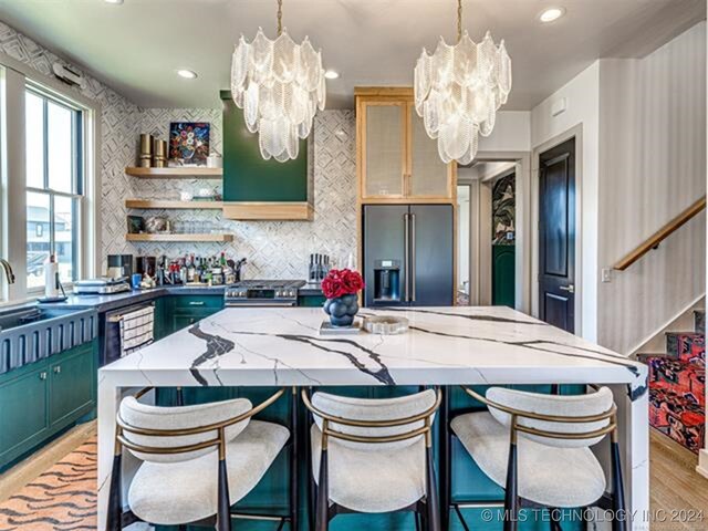 kitchen with a kitchen island, a notable chandelier, light wood-style flooring, and high end refrigerator