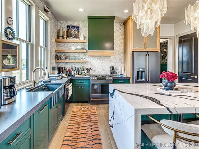 kitchen featuring light wood-style flooring, stainless steel appliances, a sink, green cabinets, and range hood