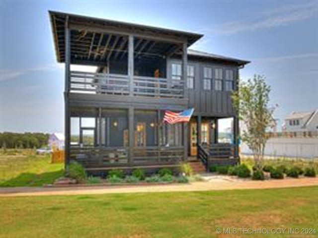 rear view of house featuring a balcony and a yard