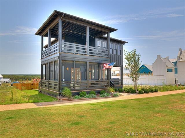 view of front of property featuring a sunroom, a front yard, fence, and a balcony