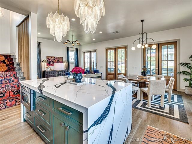 kitchen with light stone counters, a notable chandelier, light wood-style floors, open floor plan, and french doors