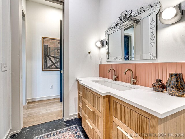 bathroom with marble finish floor, vanity, and baseboards