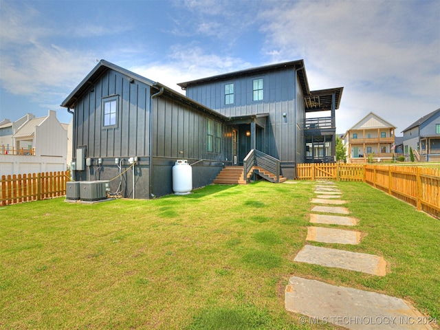 rear view of house with a fenced backyard, central AC, a lawn, and board and batten siding