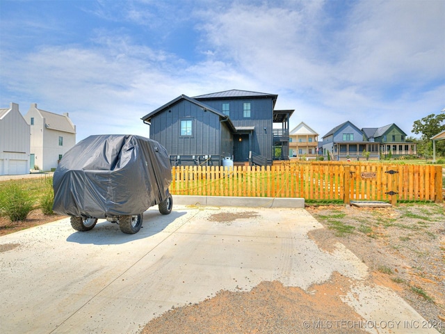 exterior space featuring a standing seam roof, a fenced front yard, a residential view, and board and batten siding