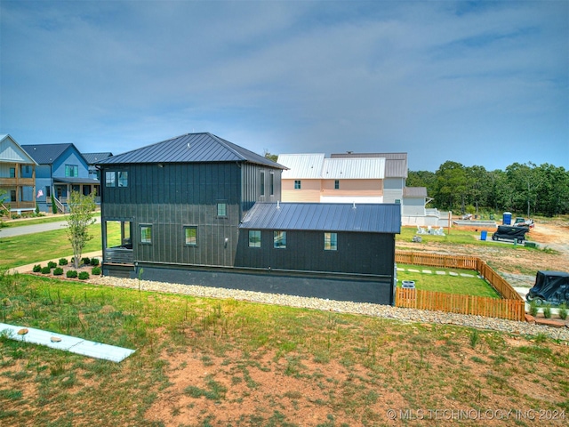 view of front of home with a standing seam roof, metal roof, a front lawn, and fence