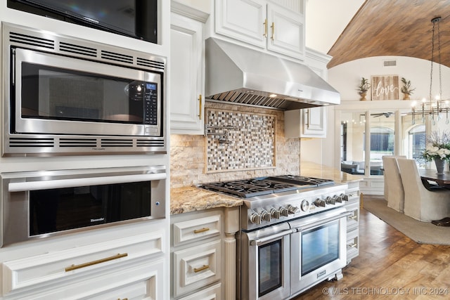 kitchen featuring dark hardwood / wood-style flooring, a notable chandelier, range hood, appliances with stainless steel finishes, and white cabinetry