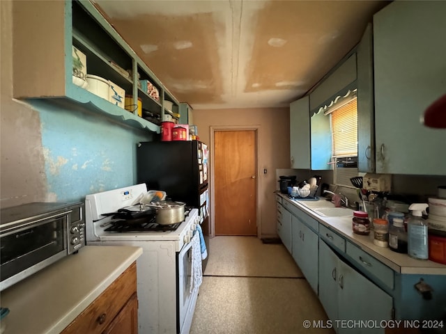 kitchen featuring white range with gas stovetop, sink, and black fridge