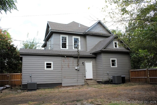 rear view of house with entry steps, a shingled roof, fence, and central air condition unit