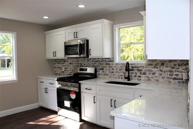 kitchen featuring appliances with stainless steel finishes, white cabinetry, sink, dark wood-type flooring, and tasteful backsplash