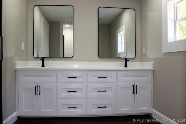 full bathroom with double vanity, a sink, and baseboards