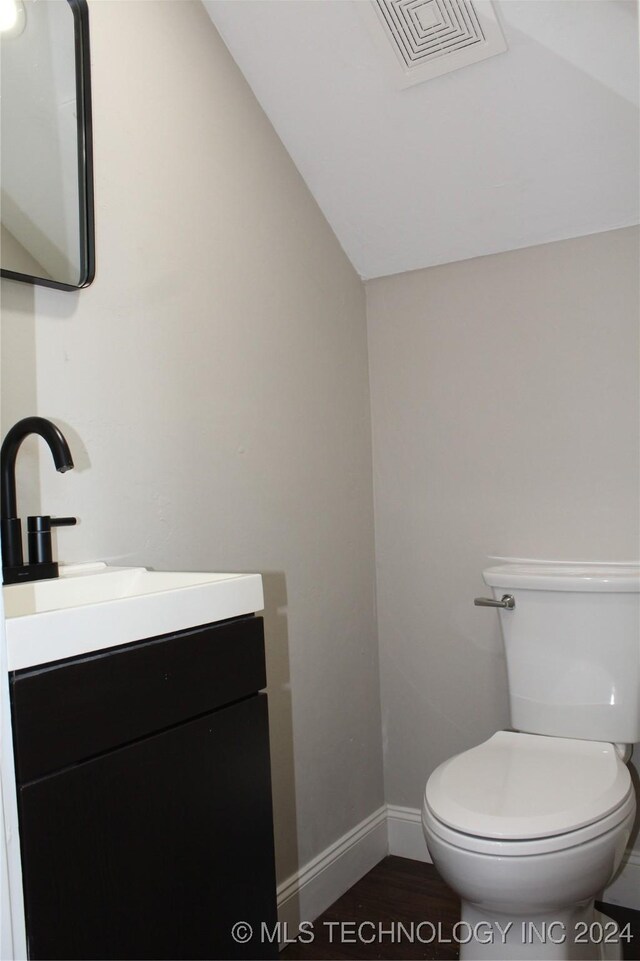 bathroom with vanity, vaulted ceiling, toilet, and wood-type flooring