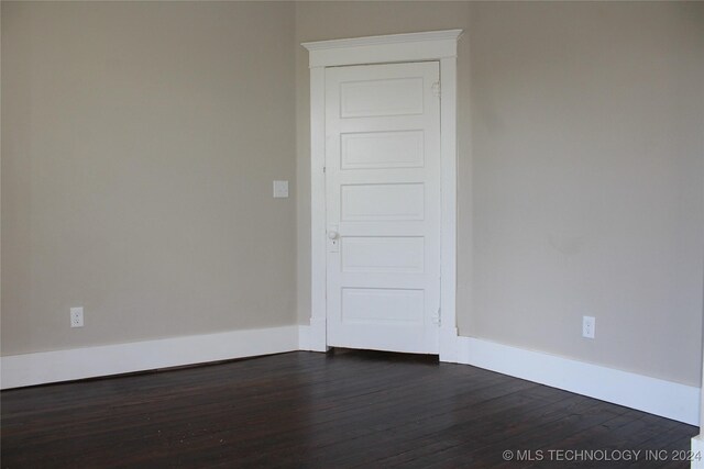 empty room featuring baseboards and dark wood-style flooring