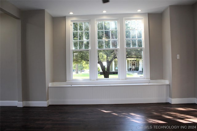 empty room featuring dark wood-type flooring, a wealth of natural light, and baseboards