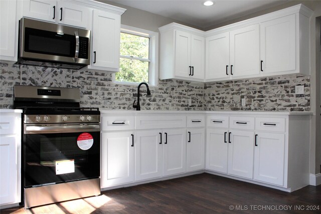 kitchen featuring white cabinets, stainless steel appliances, sink, dark hardwood / wood-style floors, and decorative backsplash