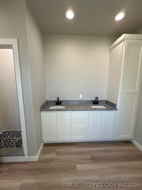 bathroom with hardwood / wood-style floors, vanity, and walk in shower