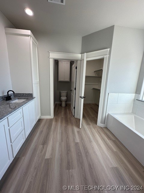 bathroom with toilet, a bathtub, vanity, and hardwood / wood-style flooring