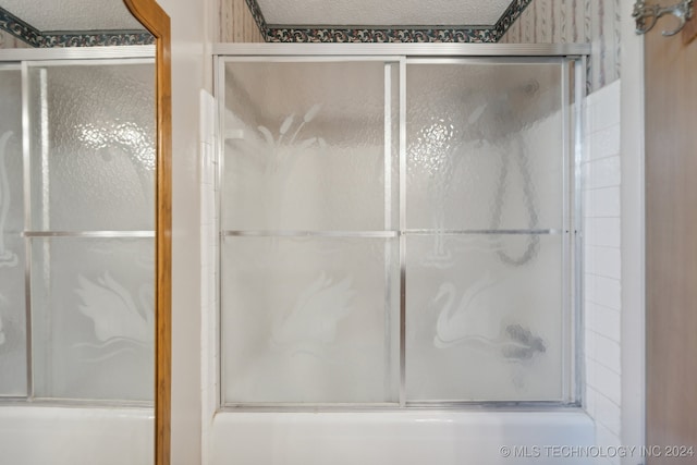 bathroom featuring a textured ceiling and enclosed tub / shower combo