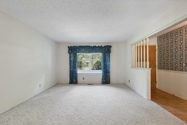 spare room with light colored carpet and a textured ceiling