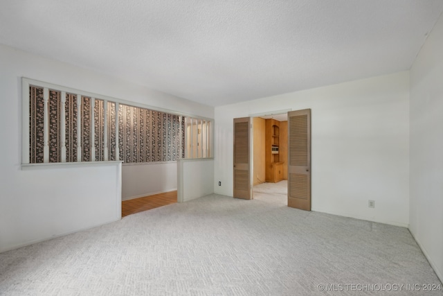 carpeted empty room with a textured ceiling