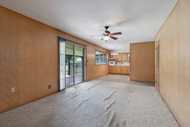 empty room featuring light colored carpet, ceiling fan, and wooden walls