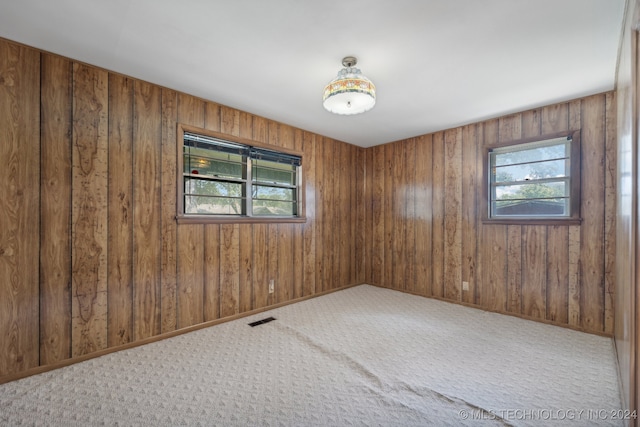 empty room with carpet and wood walls