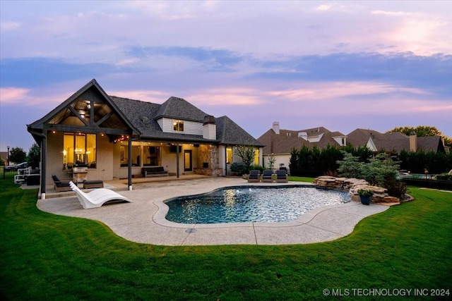 pool at dusk with an outdoor hangout area, a lawn, and a patio area