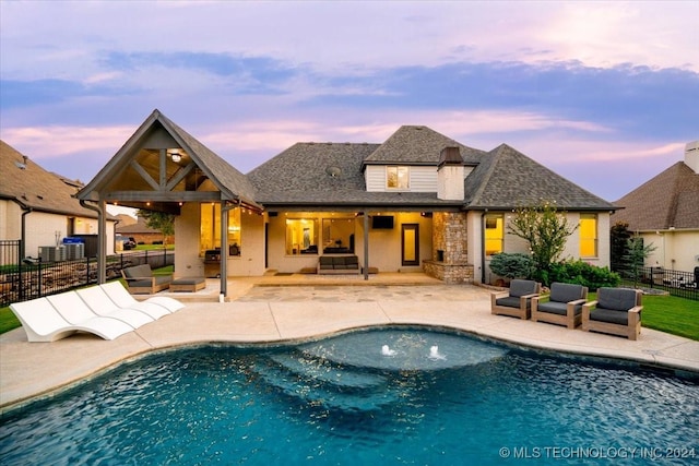 pool at dusk with an outdoor living space and a patio area