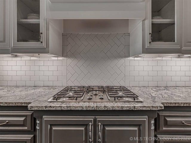 kitchen featuring tasteful backsplash, light stone countertops, and stainless steel gas cooktop