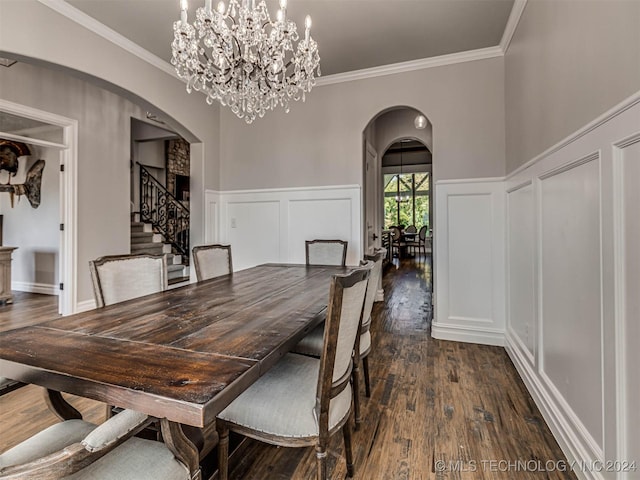 dining space featuring dark wood-type flooring, ornamental molding, and an inviting chandelier