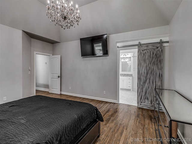 bedroom featuring an inviting chandelier, high vaulted ceiling, connected bathroom, dark hardwood / wood-style flooring, and a barn door