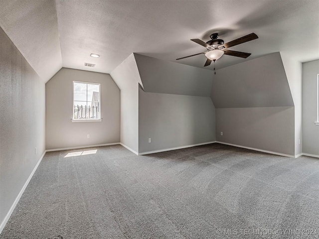 bonus room featuring vaulted ceiling, carpet, ceiling fan, and a textured ceiling