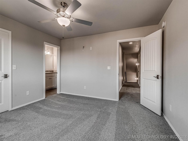 unfurnished bedroom with connected bathroom, dark carpet, and ceiling fan