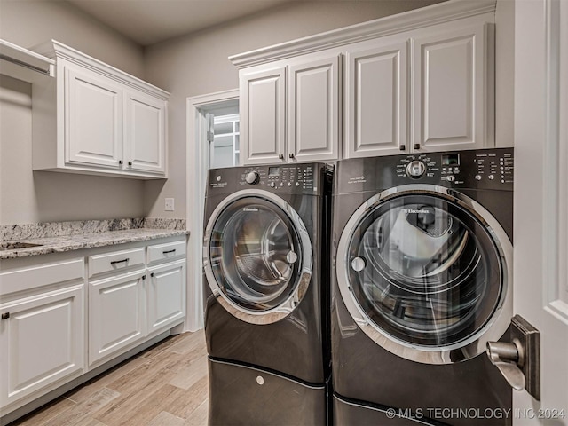 laundry room with cabinets, washing machine and dryer, and light hardwood / wood-style floors