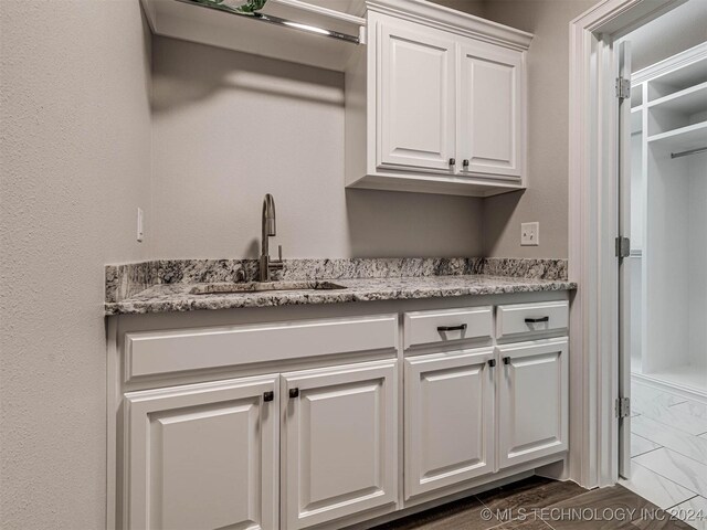 interior space with light stone counters, sink, and white cabinets